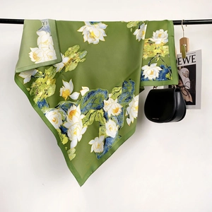 Detail of silk-like square scarf featuring green lotus prints on a minimal hanger display