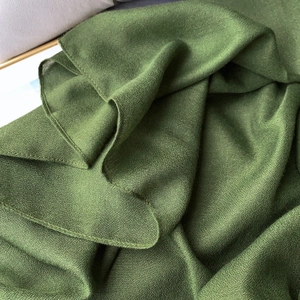 Detailed macro view of dark green linen-blend scarf fabric with fine overlock stitching