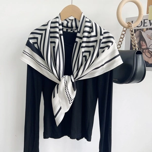 Détail d'un foulard en soie à rayures noires et blanches avec motifs géométriques sur tricot