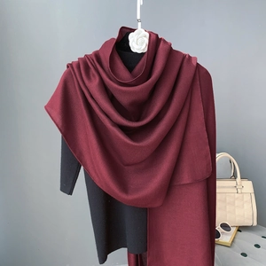 Detailed close-up of a burgundy linen shawl draped over a black outfit with accessories
