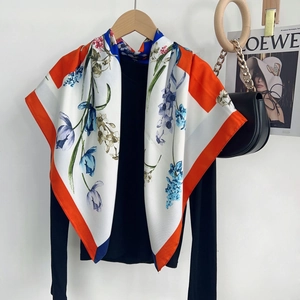 Floral silk scarf with tulip prints draped over a black knit top with a glossy finish