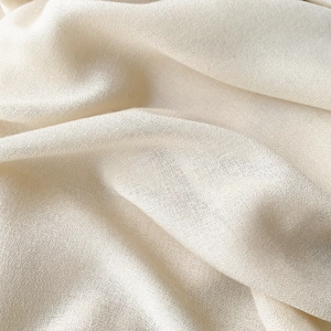 Detailed macro view showing the fine texture and soft drape of beige linen scarf fabric