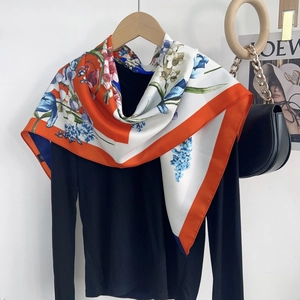 Detailed macro view of floral print silk scarf with orange borders and blue flower patterns