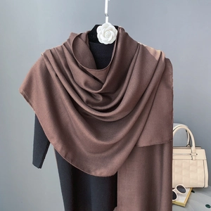 Detail showing the fine crinkle texture and drape of a chocolate brown cotton linen scarf