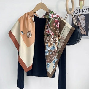 Detail of silk scarf with floral print and tulip pattern draped over a black sweater