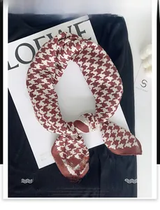 Detailed texture of red and white houndstooth pattern on a glossy silk-like square scarf