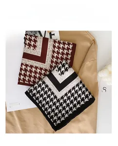Detailed view of classic houndstooth silk scarves in burgundy and black with chic props