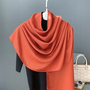 Close-up of bright orange linen scarf draped on mannequin with white fashion accessories