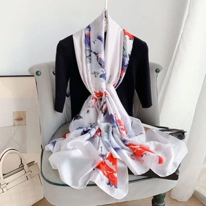Dettaglio della trama di una sciarpa in seta bianca con stampe floreali artistiche rosse