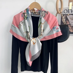 Detailed view of floral print silk scarf with pink borders and elegant draping texture