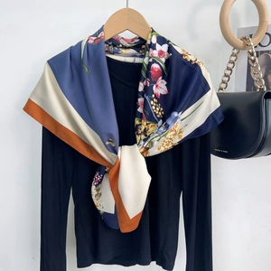 Detail of floral printed silk scarf with blue and orange geometric patterns on black top