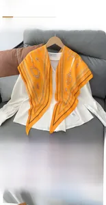 Detail of an orange rhombus silk scarf with vintage key patterns on a white shirt