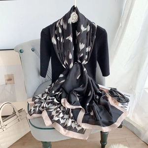 Detail of silk-like long scarf featuring white floral prints and soft pink borders