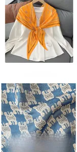 Detail of a bright orange chain print silk scarf paired with a white shirt and fabric texture