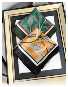Detailed view of satin floral scarves with leaf prints in green and orange tones