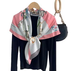 Floral print silk scarf featuring rabbit and plant patterns on wooden hanger