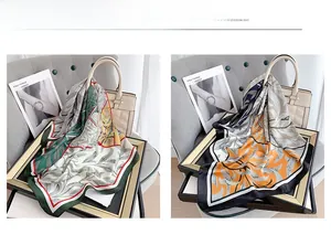 Close-up of elegant square silk scarves in green and orange tropical leaf patterns on bags