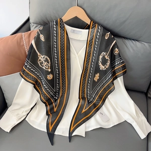 Close-up of green silk scarf with chain pattern and orange stripes on white shirt