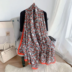 Detail of grey silk shawl featuring floral patterns and bold orange contrast borders