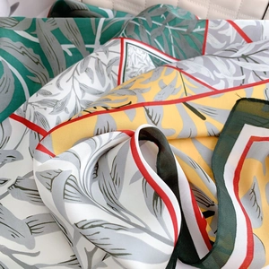 Elegant silk scarf with green botanical leaf print and red borders on white background