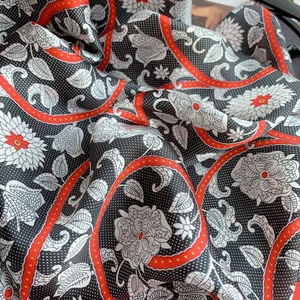 Detailed close-up of floral print silk scarf with classic polka dots and red borders