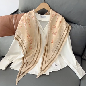 Close-up of champagne silk scarf with vintage key patterns on a white shirt