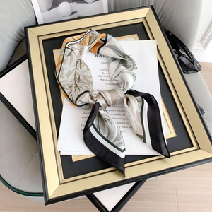 Detailed view of elegant silk scarf featuring botanical leaf patterns with warm orange accents