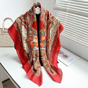 Detail of red floral paisley silk scarf draped with a decorative white floral clip