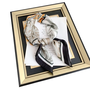 Elegant silk scarf with botanical leaves and black border in a golden frame