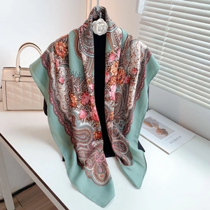 Detail of mint green paisley scarf with floral patterns on a display stand