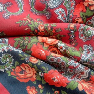 Macro shot of ethnic style red shawl featuring complex paisley patterns and floral weave