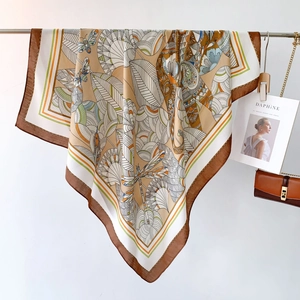 Detailed close-up of patterned silk scarf featuring floral and butterfly motifs in warm tones