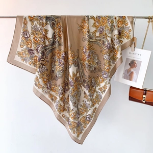 Dettaglio di sciarpa in seta con motivi floreali paisley etnici e bordo marrone