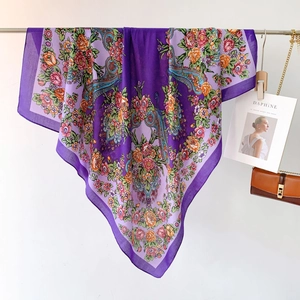 Dettaglio di grande foulard viola con motivi floreali paisley e bordo tinta unita
