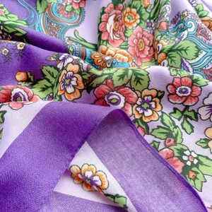 Primo piano di un foulard quadrato viola con motivi floreali retrò e trama twill