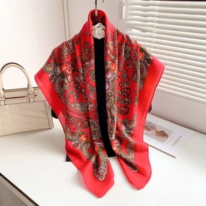 Detail of red paisley scarf with roses and white camellia brooch on a display stand