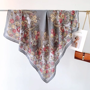 Dettaglio di sciarpa quadrata in seta grigia con motivi floreali e paisley ed accessori