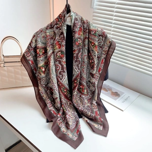 Close-up of elegant paisley print square scarf draped on a black clothing display stand