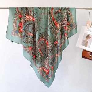 Close-up of soft paisley and red rose patterns on a green silk-feel square scarf