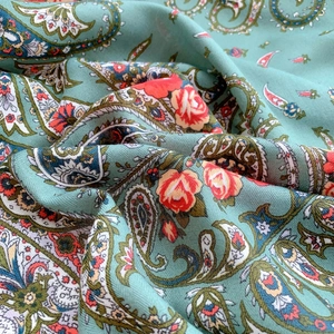 Detailed close-up of paisley pattern and floral print on bean green velvet-touch fabric