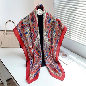 Elegant large silk scarf with red border and paisley patterns on a display stand
