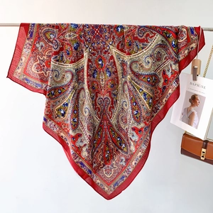 Detailed close-up of premium red paisley square scarf with silk texture and boho floral prints