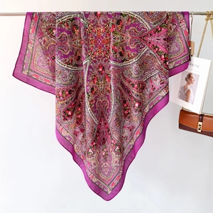 Detailed view of magenta silk shawl with paisley and rose patterns in a flat lay setup