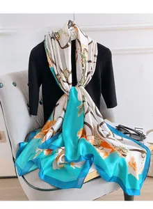 Detail of luxury silk scarf with orange floral prints and blue chain pattern accents