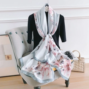 Elegant magnolia flower silk scarf in light blue with floral print on a fashion mannequin