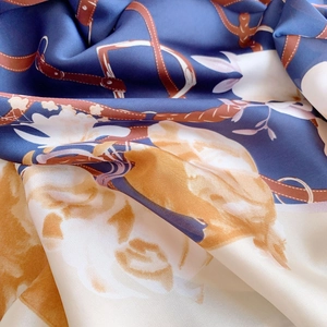 Detail of silk-like scarf featuring classic belt and metal buckle print pattern