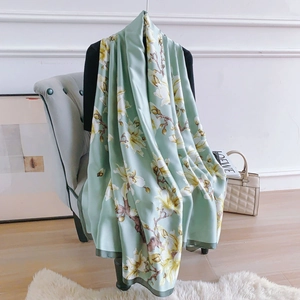Detailed view of elegant light green silk scarf with lifelike magnolia floral patterns