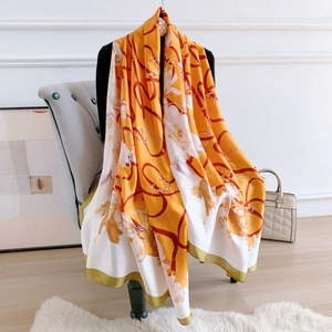 Detail of silk-like scarf with yellow horsebit chain print draped in elegant setting