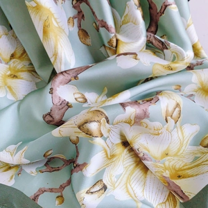 Close-up of floral magnolia silk scarf fabric with elegant mint green satin texture