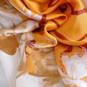 Detail of floral silk scarf showing smooth texture and elegant orange flower patterns